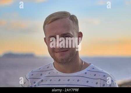 Handsome blond man on blue sky background at sunny day Stock Photo