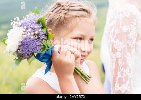 A cute little touching child and an amazing wedding bouquet of white and purple peonies at her parents' wedding Stock Photo