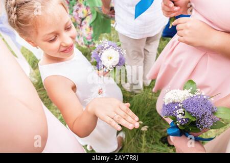 Little sweet girlfriend of the bride brags her rings to grown-up girlfriends Stock Photo