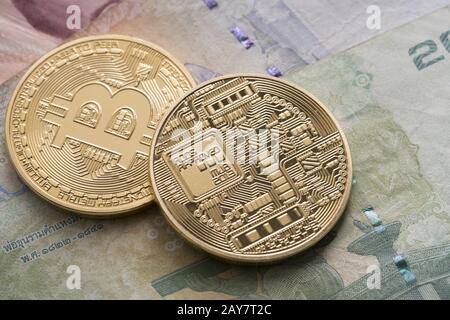 Two golden bitcoin on some bills close up shot Stock Photo