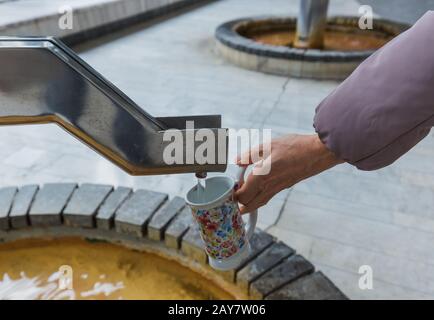 Tourist pours mineral water from the source in Karlovy Vary - Czech Republic Stock Photo