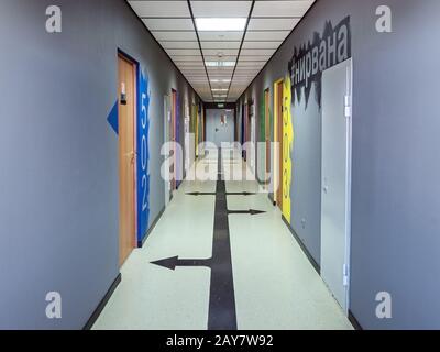 Sochi, Russia - 13 October 2019. View of long gray corridor in a hotel with color airbrushing near doors and black arrows on the floor Stock Photo