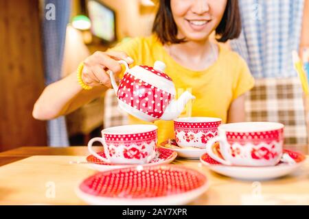 A girl in a cafe pours tea from a teapot into a mug. Stock Photo