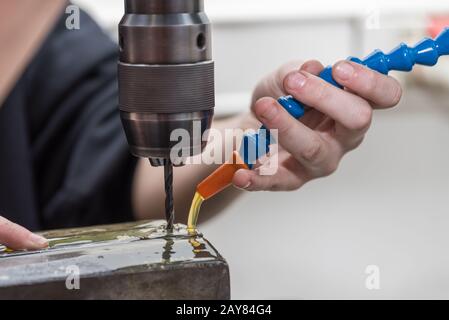 Drill a hole in steel with a metal drill bit using coolant - Nautical Stock Photo