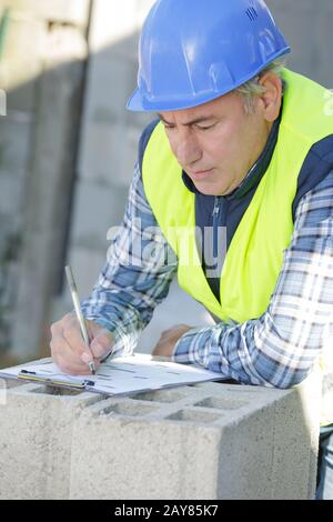 man in a safety hat taking notes on a factory Stock Photo