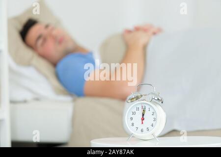 alarm clock waking sleeping man in bed Stock Photo