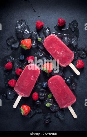Refreshing popsicle on ice cubes and fruits Stock Photo