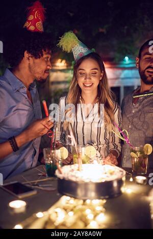 birthday girl in front of cake making a wish before blowing the candles. birthday, wish, friends concept Stock Photo