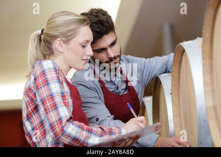 two staff inspecting barrels in a wine factory warehouse Stock Photo