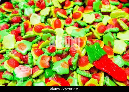Bright green, yellow, white and red marmalade gummies in the shape of strawberries. Sweet beautiful delicacy made from gel fruit juices. Colorful back Stock Photo