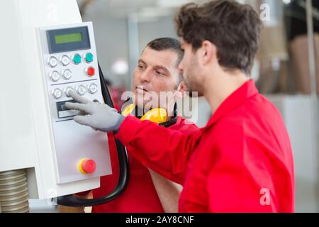 workers operating cnc metal skip in factory Stock Photo