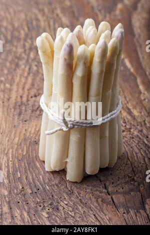 Row of white asparagus on dark wood Stock Photo