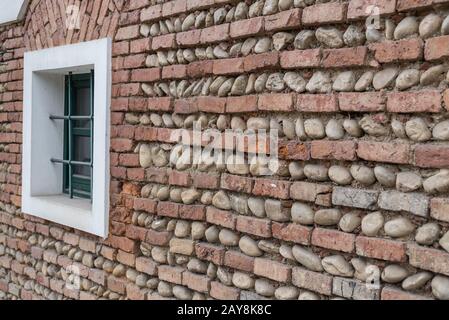 Oblique view of a wall of bricks and river stones with window Stock Photo