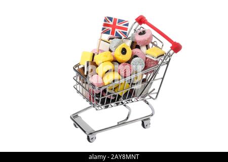 Top view of a shopping cart decorated with a Brttish flag and filled with assorted licorice candy isolated on white background. Stock Photo