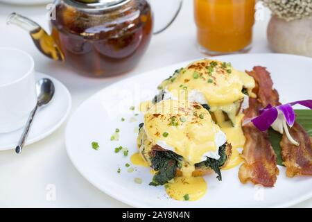 Close up fresh egg Benedict breakfast with Black coffee and orange juice. Stock Photo