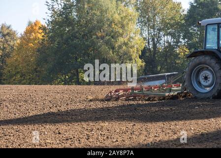 Farmer works the soil with tractor and harrow - detail Stock Photo