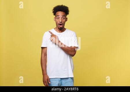 Astonished young African American man dressed in casual white shirt having excited fascinated look, pointing index finger at cop Stock Photo