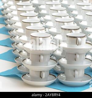 White coffee cups with plates stand stacked in a row Stock Photo