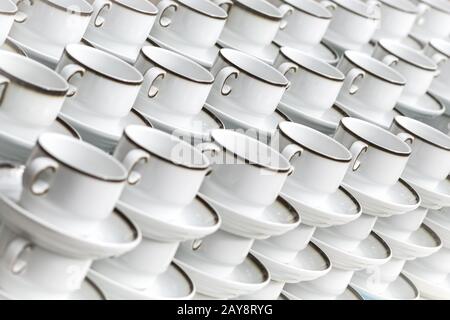 White coffee cups with plates stand stacked in a row Stock Photo