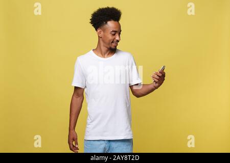 Happy african american man with smiling and using mobile phone. Isolated on yellow background. Stock Photo
