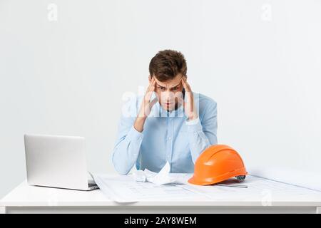 Portrait of engineer stress holding his head with hand sitting at the table and feel headache in the office on isolated backgrou Stock Photo