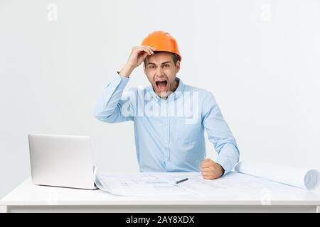 Young Engineer angry during working with laptop in office building site, he has problems with his new project manager Stock Photo