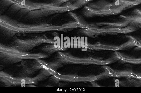 Wave patterns on sand by the beach in black and white close-up in landscape Stock Photo