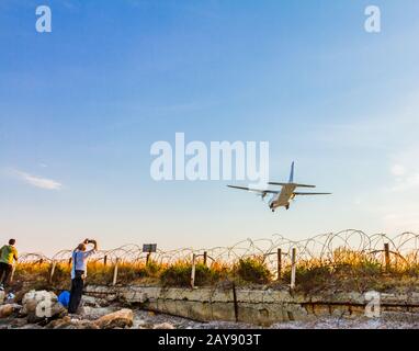 People photographing a turboprop airplane landing at Larnaca International Airport Stock Photo