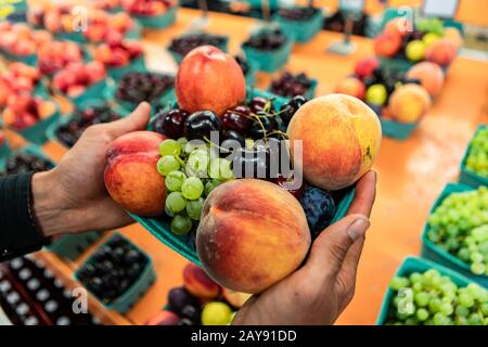 Close up neatly arranged cardboard boxes of beautiful mixed fruits. Fresh and organic plump fruit on sale at the local market. Selective focus. Stock Photo