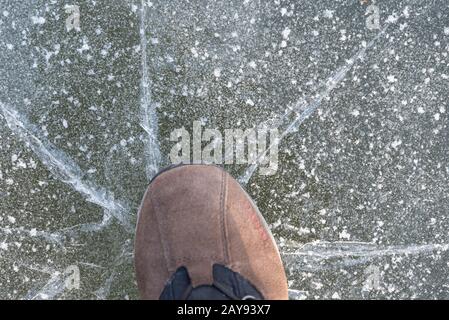 Person on breaking thin layer of ice - close-up Stock Photo