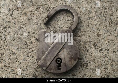 Old weathered grunge retro open padlock closeup on solid stone surface background Stock Photo