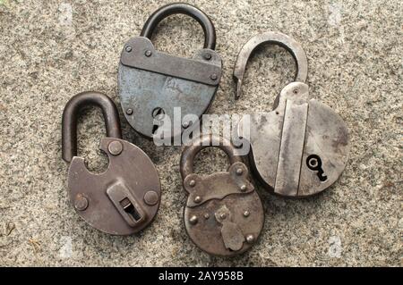 Old weathered grunge retro open and locked padlocks closeup on solid stone surface background Stock Photo