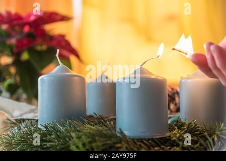 first candle on Advent wreath is lit with match - close-up Stock Photo