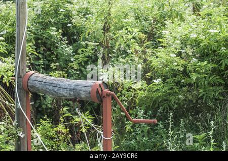 Old rural water well wooden hand crank element closeup in summer country garden Stock Photo