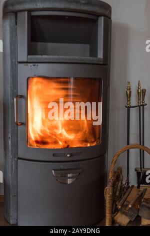 Warming fire with firewood in the window of the nostalgic wood stove - piece wood Stock Photo