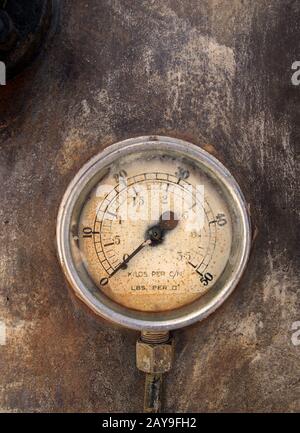 an old round pressure meter with numbers on the gauge on a rusty metal background Stock Photo