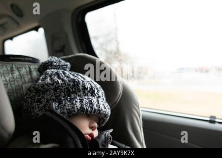 Toddler wearing winter hat sleeps while in carseat inside minivan Stock Photo