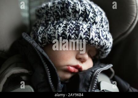 Close-up of toddler boy asleep in carseat while traveling in car Stock Photo