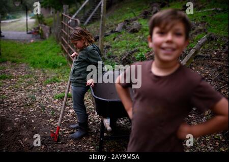 Child with shovel looking down at the ground with boy in foreground Stock Photo