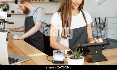 Coffee Business Concept - beautiful caucasian bartender barista or manager Posting order in digital tablet menu at modern coffee Stock Photo