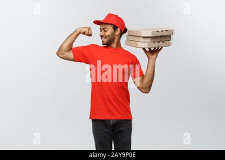 Delivery Concept - Portrait of Strong African American delivery man showing his muscle with pizza box packages. Isolated on Grey Stock Photo