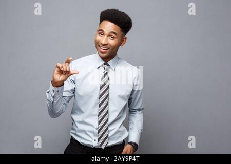 Business Concept - Amazed African American holding both hands on side presenting projects over grey background. Stock Photo