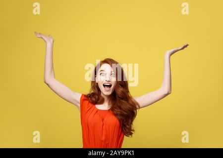 Lifestyle Concept: Happy excited cuacaisan tourist girl pointing finger on copy space isolated on golden yellow background Stock Photo