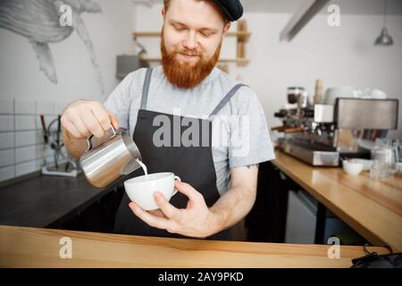 Coffee Business Concept - handsome bearded man in apron making coffee while standing at cafe Stock Photo