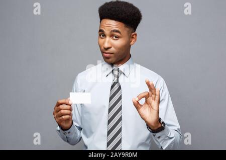 Business Concept - Happy handsome professional african american businessman showing name card to client. Stock Photo