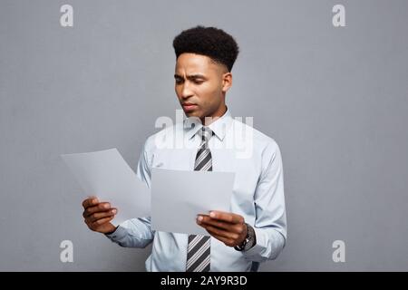 Business Concept - handsome young professional african american businessman concentrated reading on document paper. Stock Photo