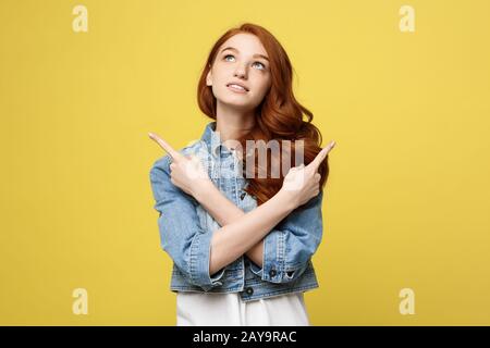 Lifestyle Concept: Happy excited cuacaisan tourist girl pointing finger on copy space isolated on golden yellow background Stock Photo