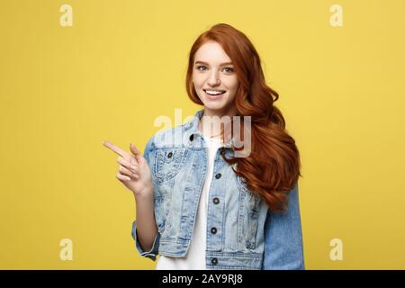 Lifestyle Concept: Happy excited cuacaisan tourist girl pointing finger on copy space isolated on golden yellow background Stock Photo