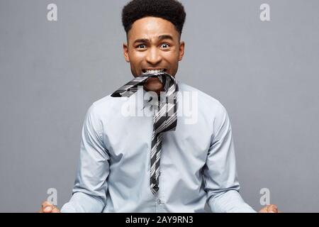 Business Concept - Angry African American with confused screaming with frustrated expression over grey background. Stock Photo