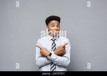 Business Concept - Confident thoughtful young African American pointing finger on side over grey background. Stock Photo